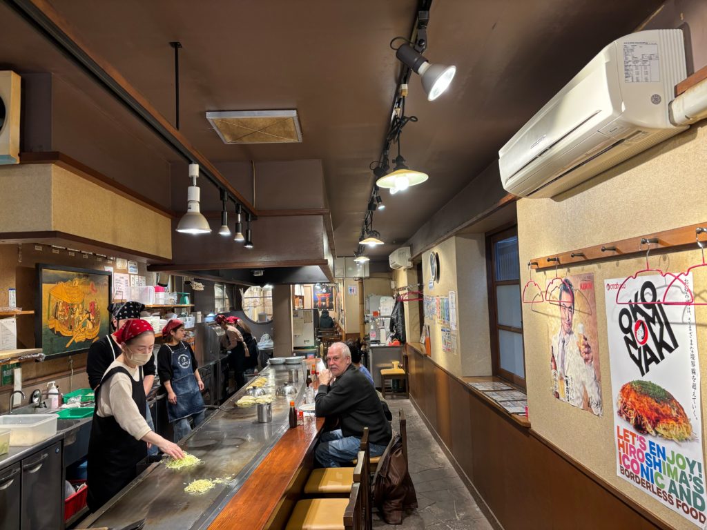 Interior view of Kurawanka okonomiyaki restaurant showing cozy traditional atmosphere with counter and table seating