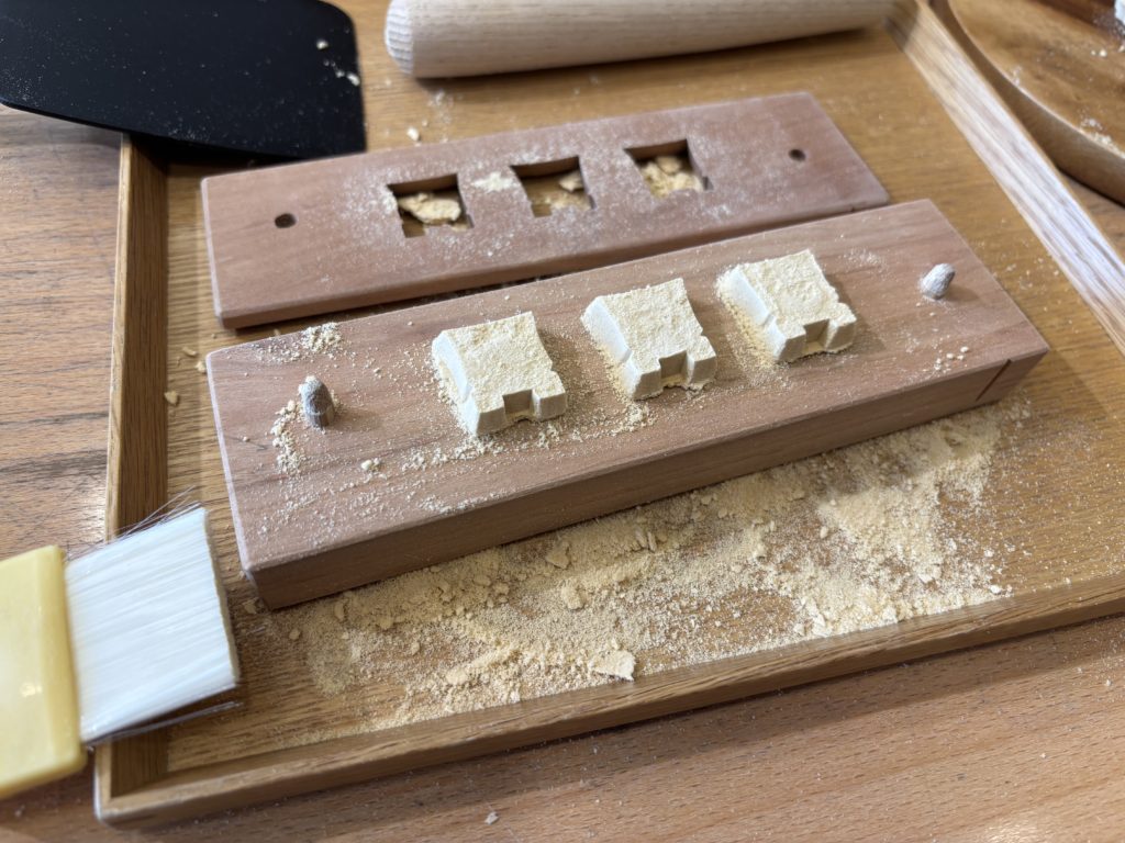 Tapping the mold sides with wooden mallet to release the formed sugar